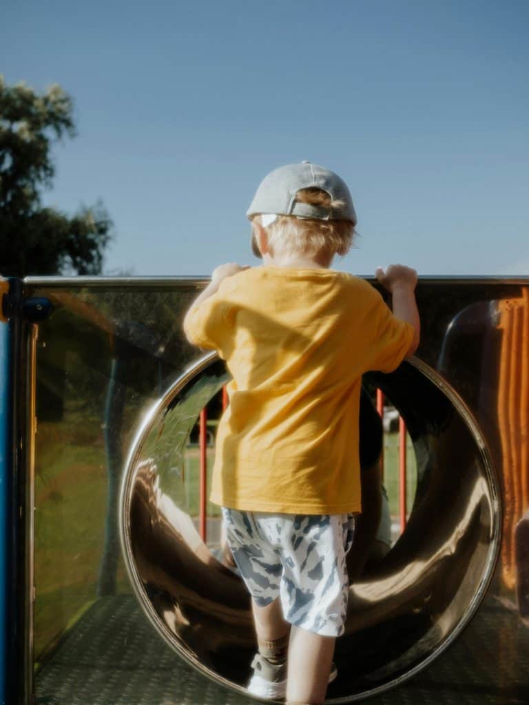 pexels-photo-12939367-12939367-1 A young child climbing a playground slide on a sunny summer day, enjoying outdoor play.