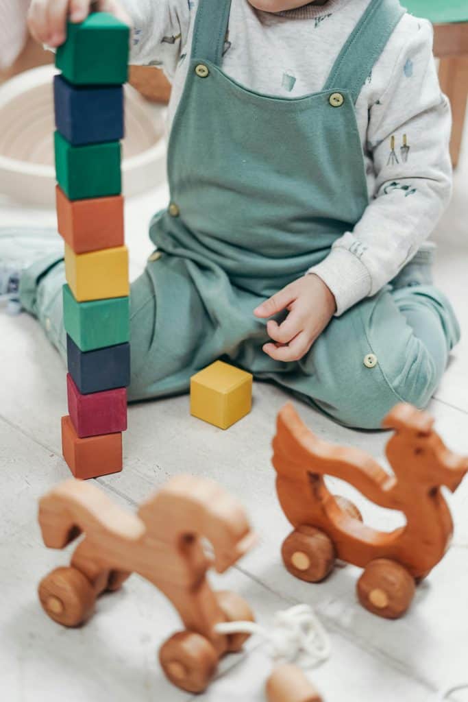 pexels-photo-3661351-3661351 A child enjoying playtime indoors with colorful wooden blocks and toys.